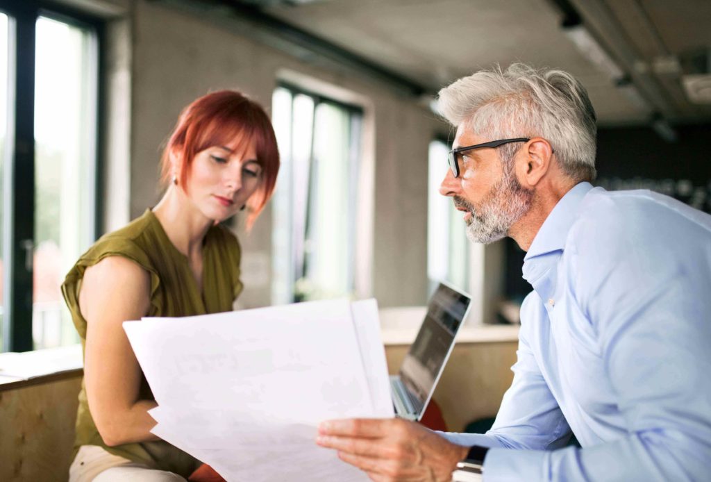 A man and woman sitting together looking at a contract that will determine their customer-client relationship