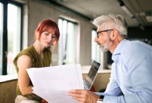A man and woman sitting together looking at a contract that will determine their customer-client relationship